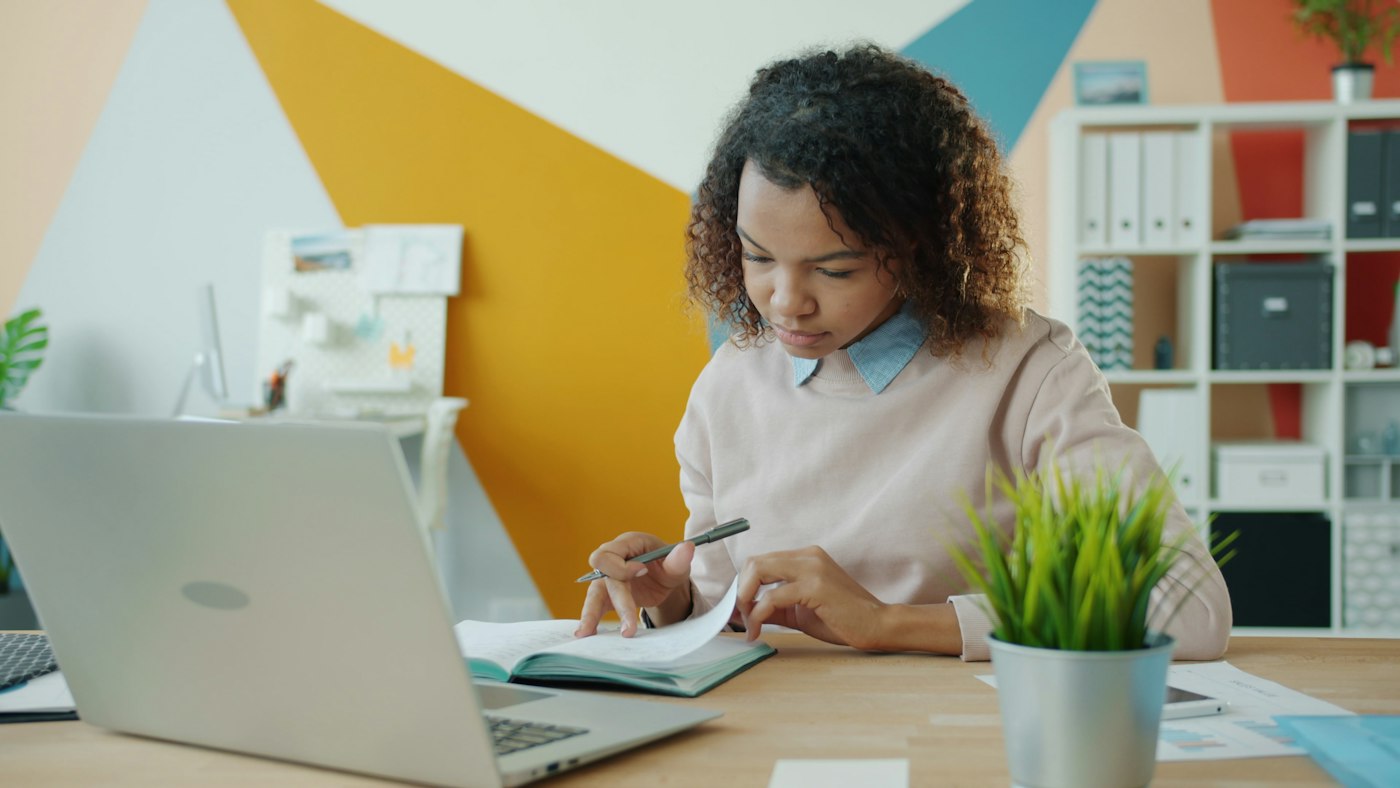 A student taking notes beside her laptop
